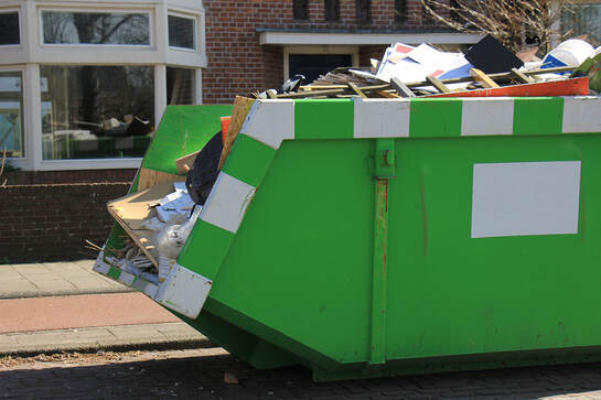 green dumpster with trash